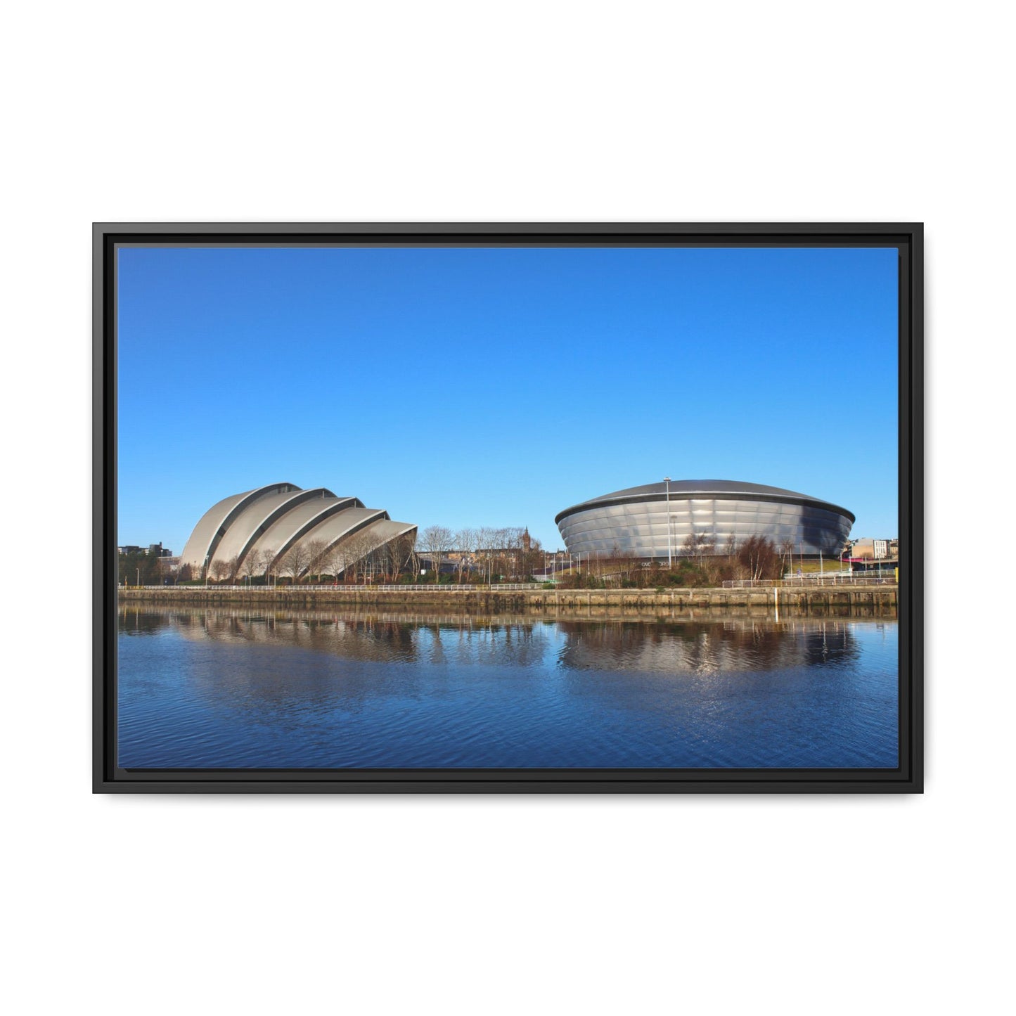 Framed photograph of a modern architectural complex with a blue sky and water reflection.