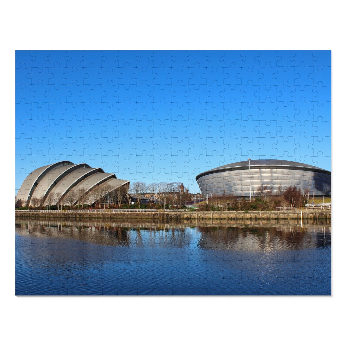 Two large, modern buildings with curved roofs reflected in a body of water under a clear blue sky.