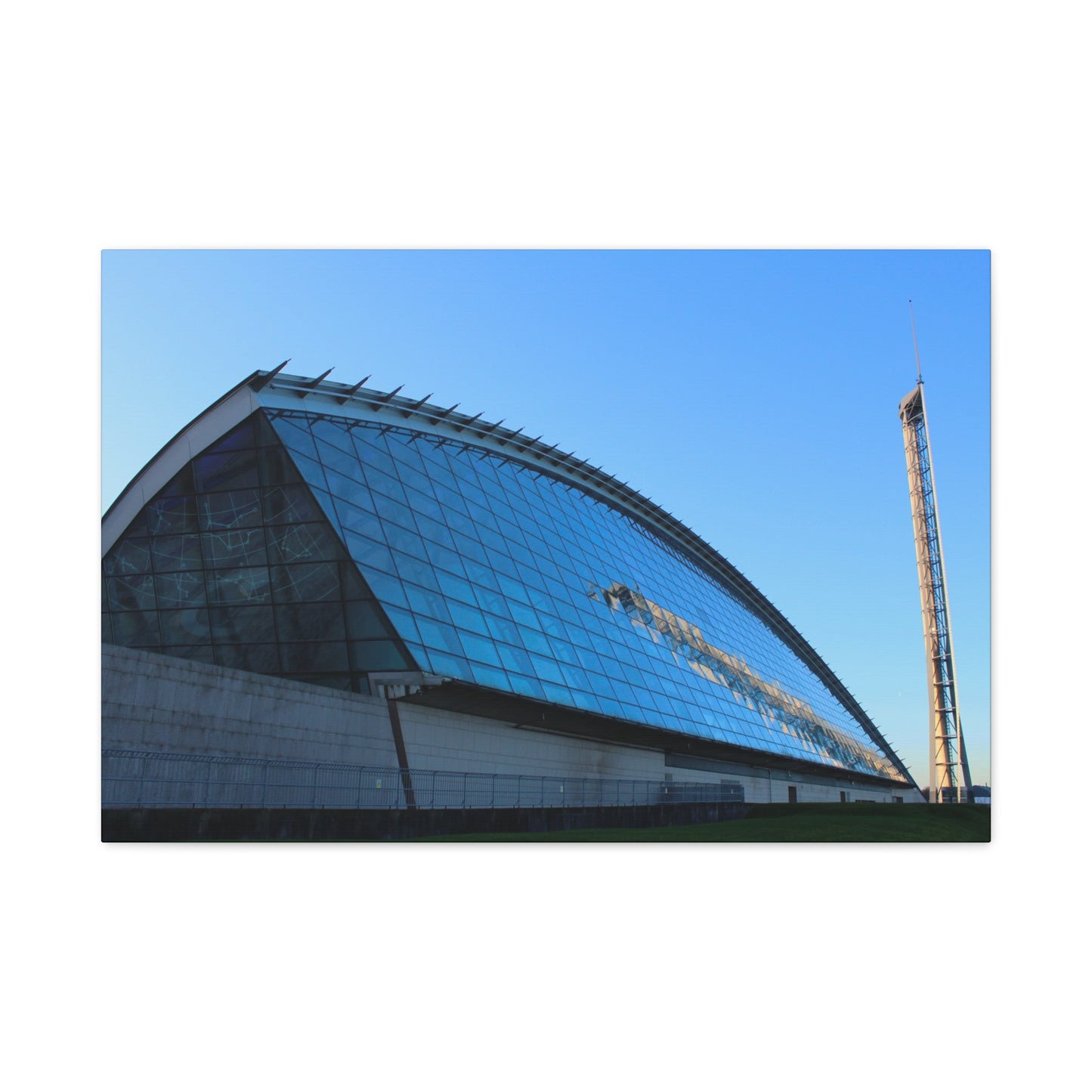 Modern architectural structure with a curved glass facade against a clear blue sky.