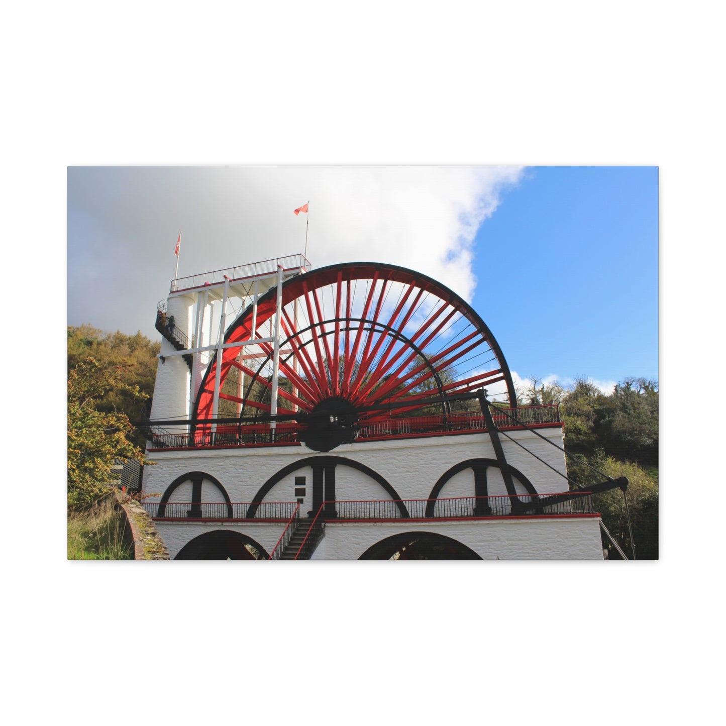 Canvas print of a large water wheel with a blue sky background
