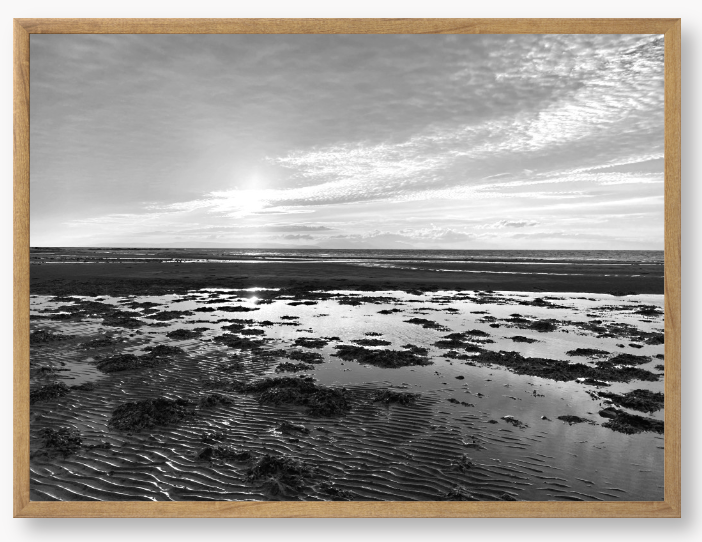 Black and white framed photograph of a coastal landscape with a sunset.