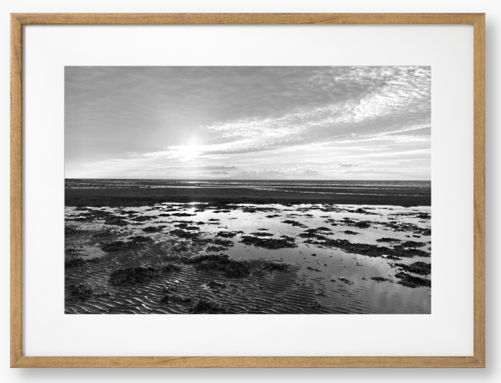 Black and white framed photograph of a coastal landscape with a sunset.