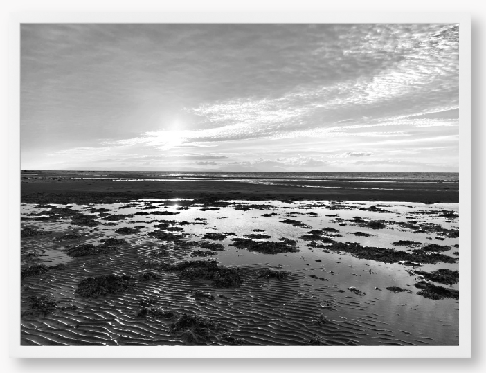 Black and white framed photograph of a coastal landscape with a sunset.