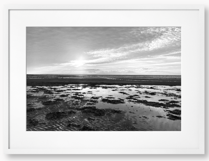 Black and white framed photograph of a coastal landscape with a sunset.