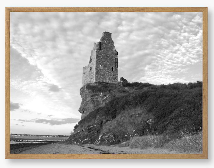 Framed black and white photograph of a tower on a cliff with a cloudy sky.