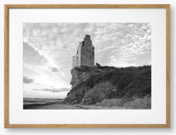 Framed black and white photograph of a tower on a cliff with a cloudy sky.