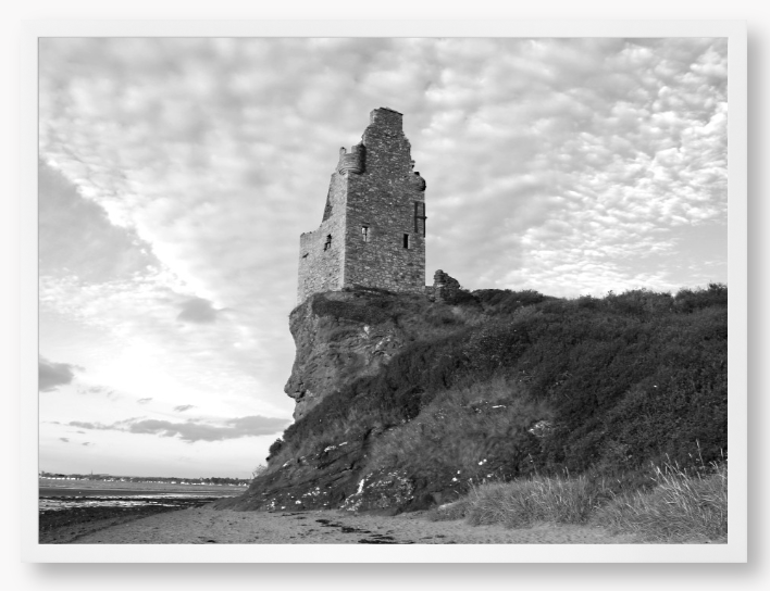 Framed black and white photograph of a tower on a cliff with a cloudy sky.