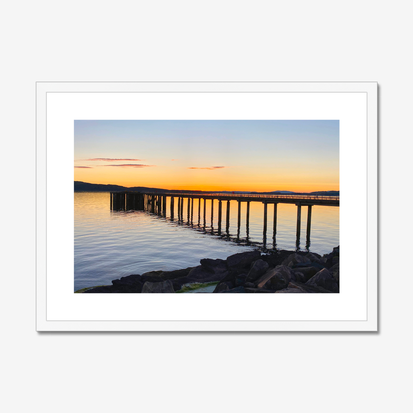 Framed photograph of a sunset over a dock with a white border