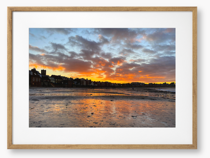 Framed Photo of a sunset over a coastal town with vibrant colours reflected in the water.