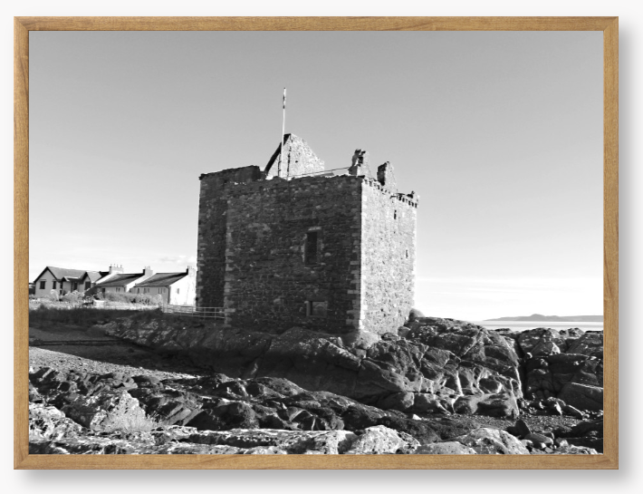 black and white Framed Photo of a Stone castle on rocky terrain with a clear blue sky