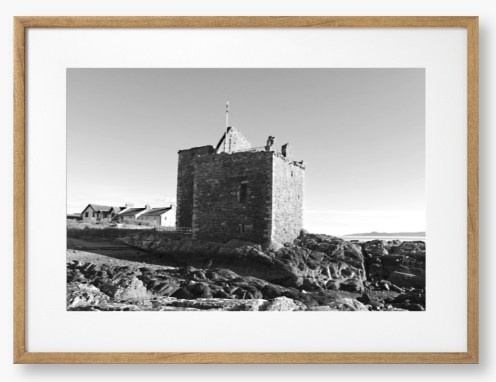 black and white Framed Photo of a Stone castle on rocky terrain with a clear blue sky