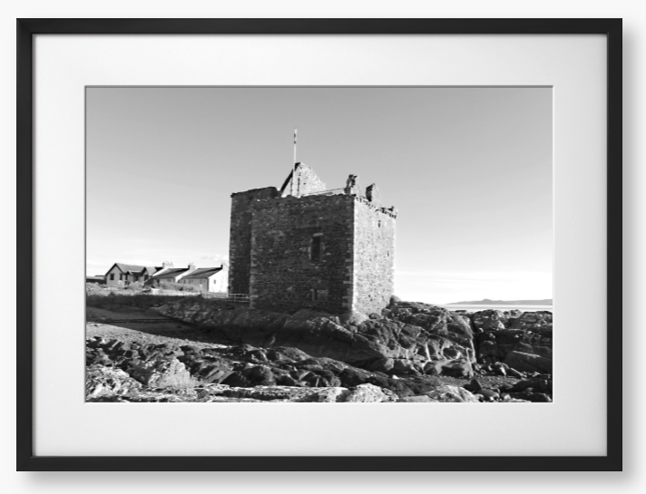 black and white Framed Photo of a Stone castle on rocky terrain with a clear blue sky