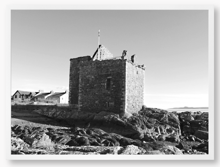 black and white Framed Photo of a Stone castle on rocky terrain with a clear blue sky
