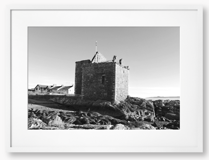 black and white Framed Photo of a Stone castle on rocky terrain with a clear blue sky