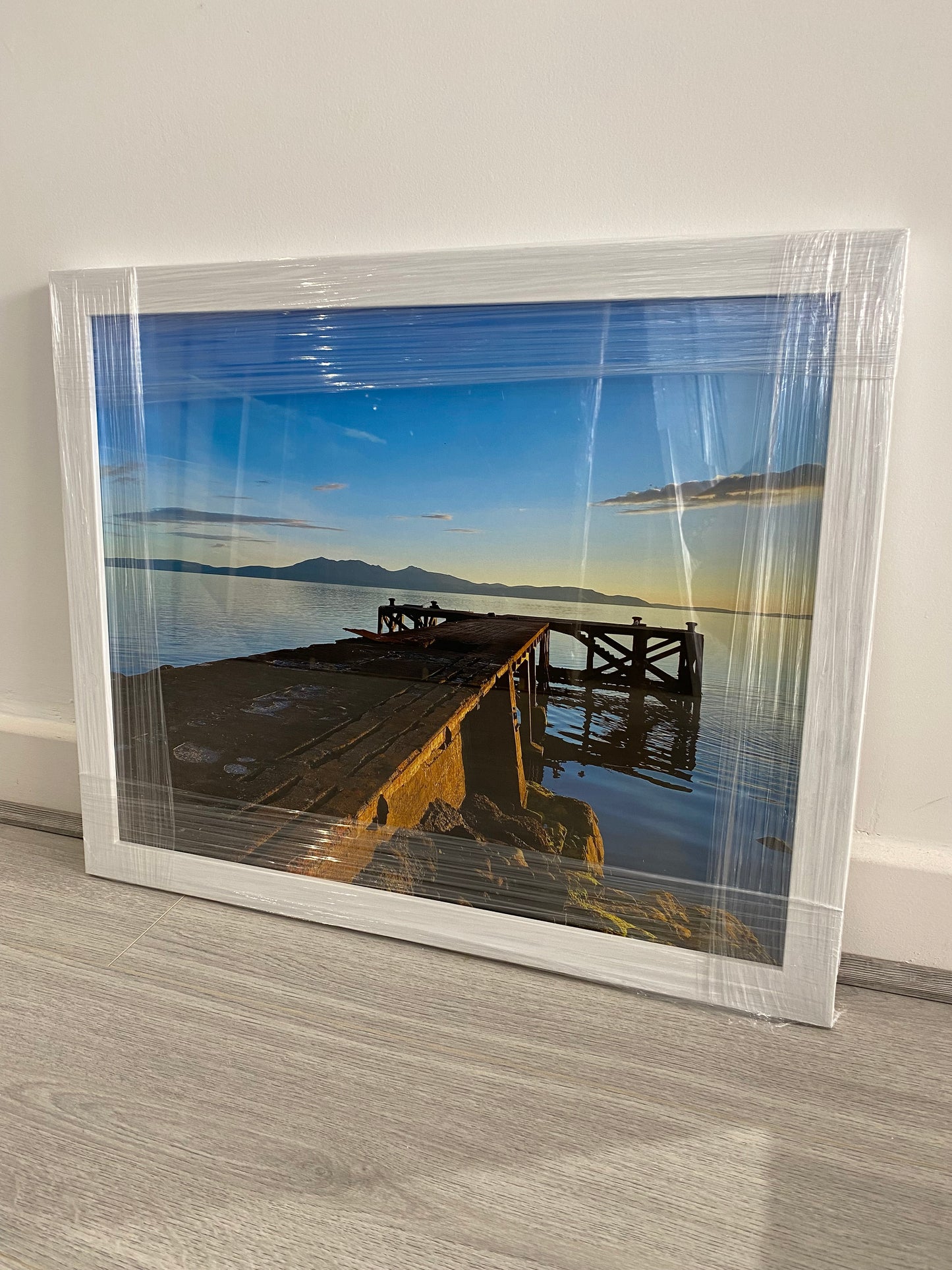 Wooden dock extending into a calm body of water with mountains in the background.