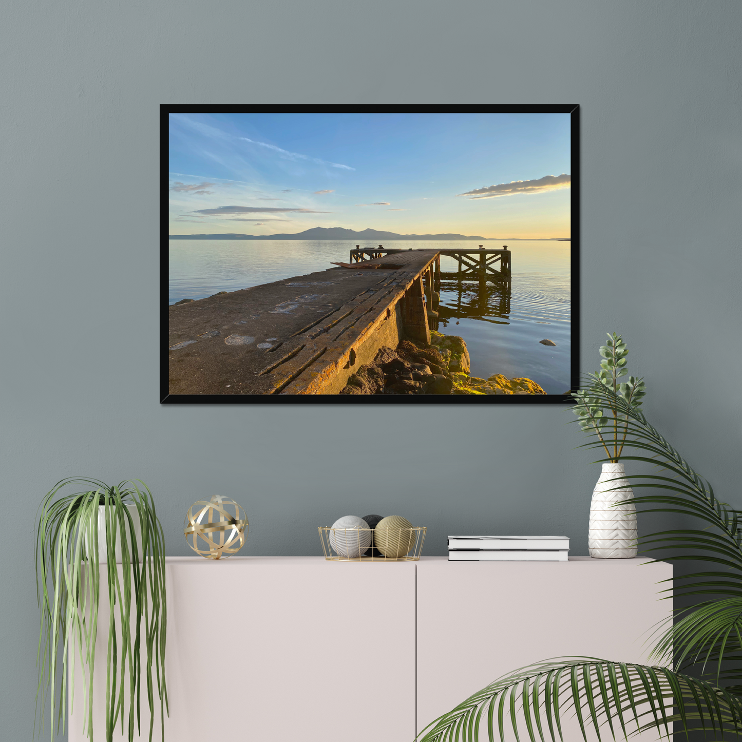Framed artwork of a cityscape with a bridge on a gray wall above a white console table.