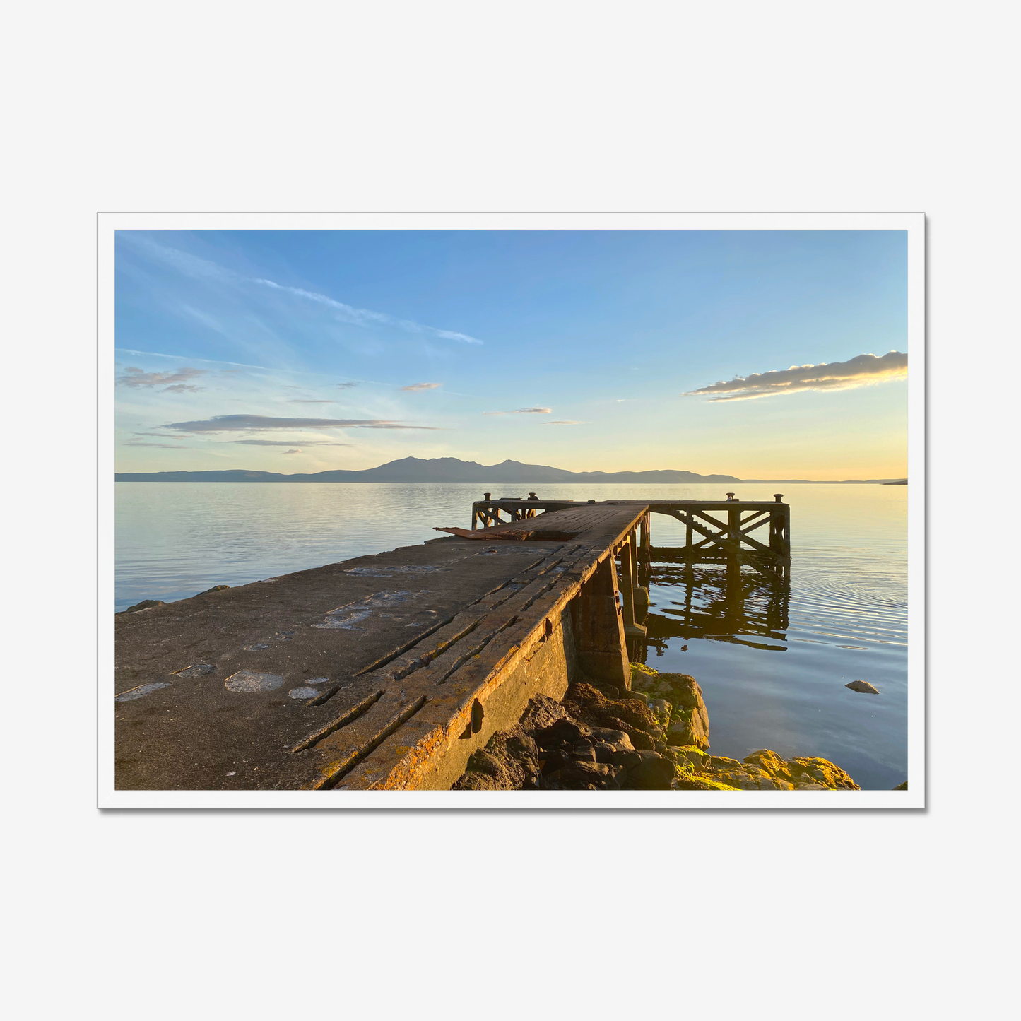 Wooden dock extending into a calm body of water with mountains in the background.