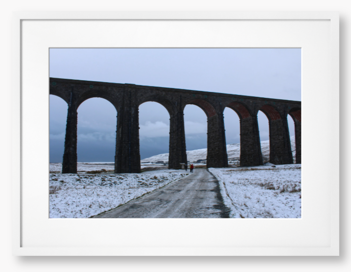 Framed Photo of a Viaduct in a snowy landscape with people walking on a path below.