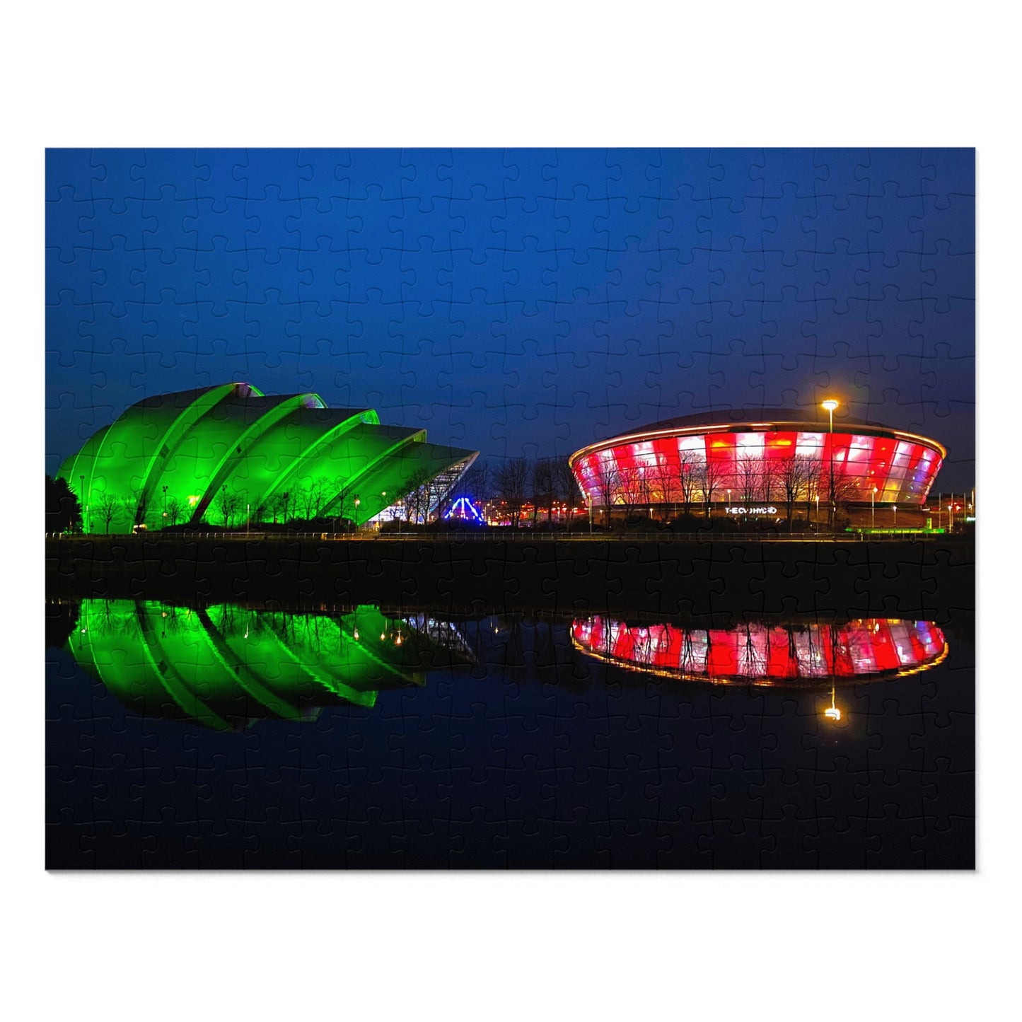 Two colorful buildings reflected in water at night