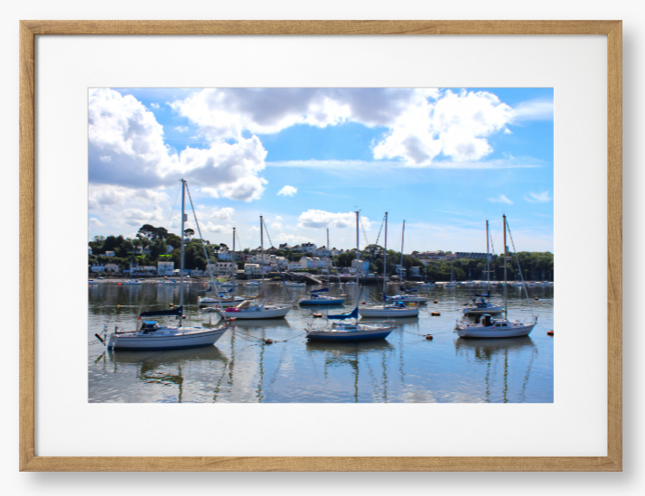 Framed Photo of a Harbour scene with boats docked in calm water under a blue sky with clouds.