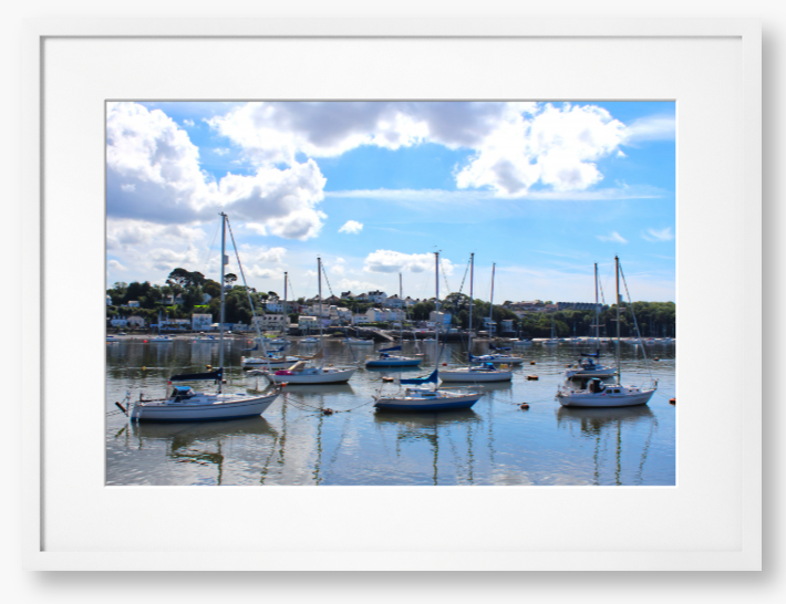 Framed Photo of a Harbour scene with boats docked in calm water under a blue sky with clouds.