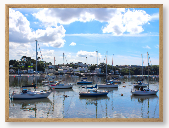 Framed Photo of a Harbour scene with boats docked in calm water under a blue sky with clouds.
