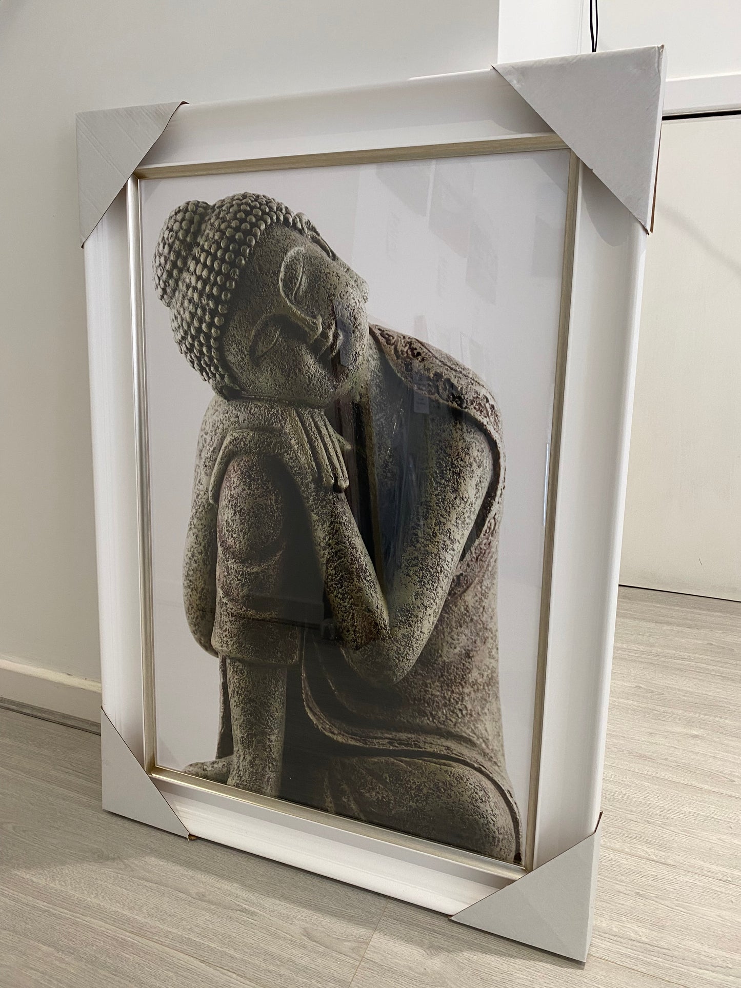 Framed sculpture of a reclining Buddha figure on a wooden surface