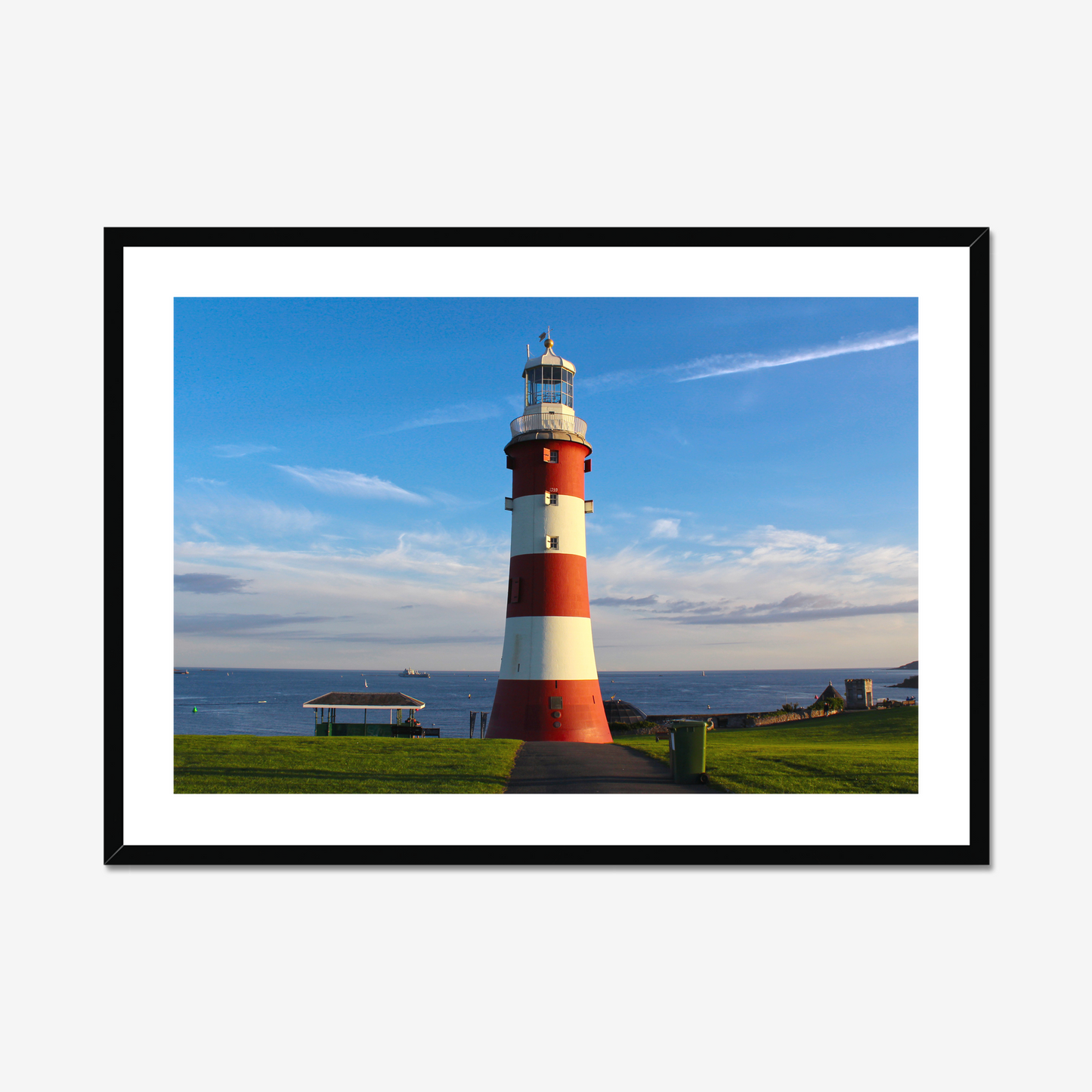 Framed picture of a red and white lighthouse by the sea