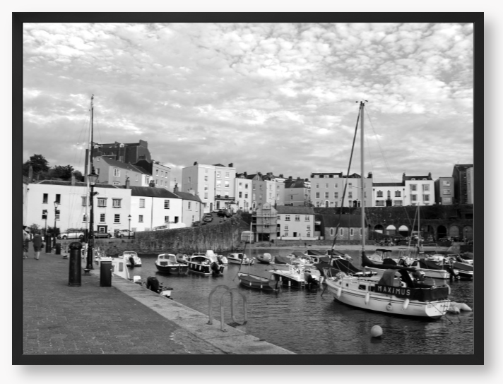 Black and white framed photo of a harbour scene with boats and buildings