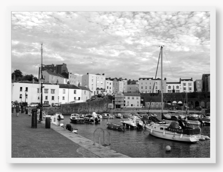 Black and white framed photo of a harbour scene with boats and buildings