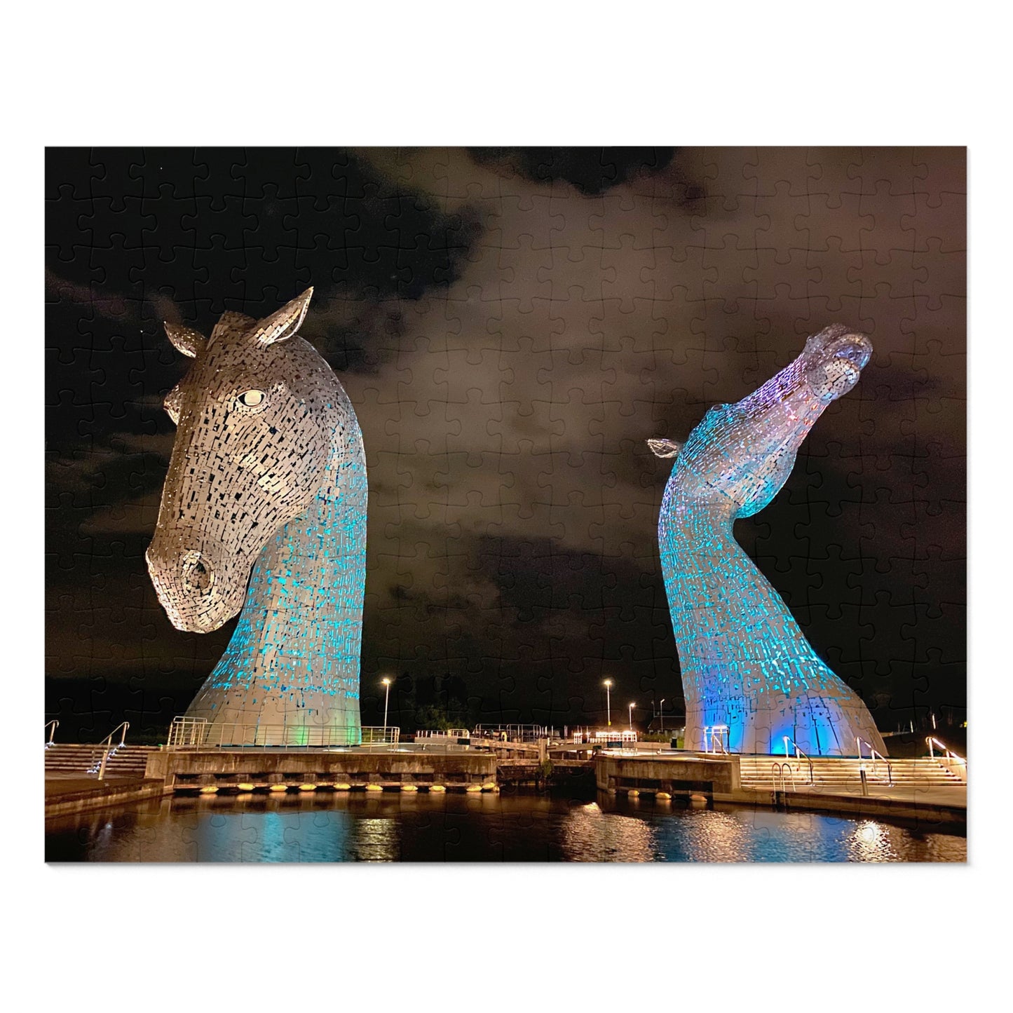 Two large horse head sculptures illuminated with blue lights against a dark sky.