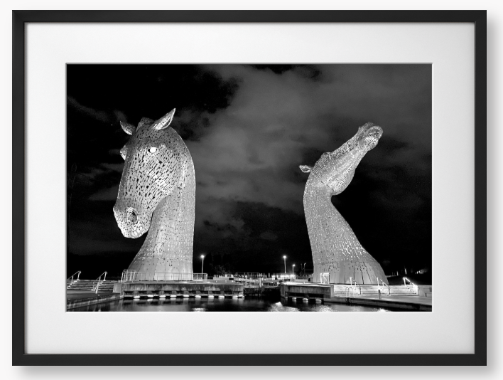 Black and White Framed Photo of the Kelpies horse sculptures in Falkirk, Scotland, illuminated at night.