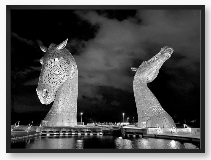 Black and White Framed Photo of the Kelpies horse sculptures in Falkirk, Scotland, illuminated at night.