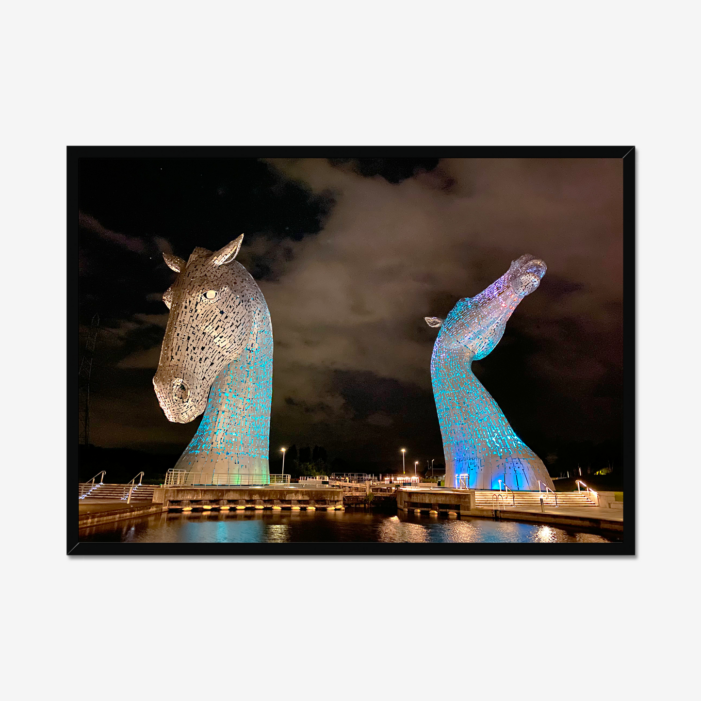 Framed artwork of two illuminated horse head sculptures against a dark sky.