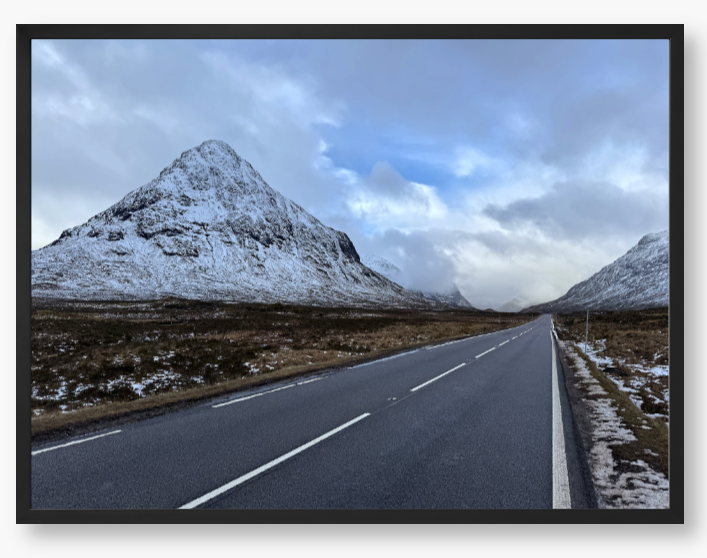 Framed Photo of a road leading towards snow-capped mountains under a cloudy sky