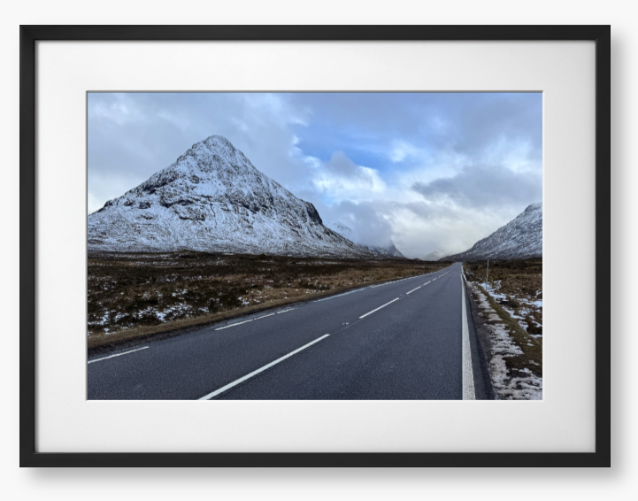 Framed Photo of a road leading towards snow-capped mountains under a cloudy sky