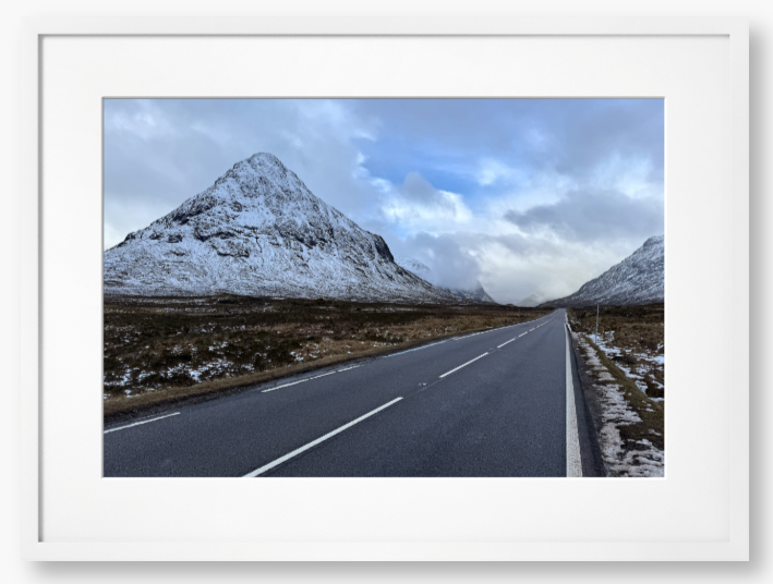 Framed Photo of a road leading towards snow-capped mountains under a cloudy sky