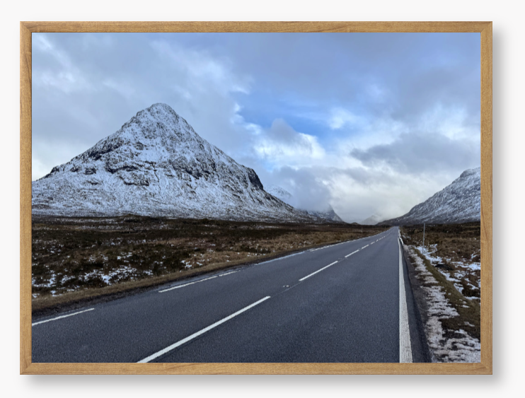 Framed Photo of a road leading towards snow-capped mountains under a cloudy sky