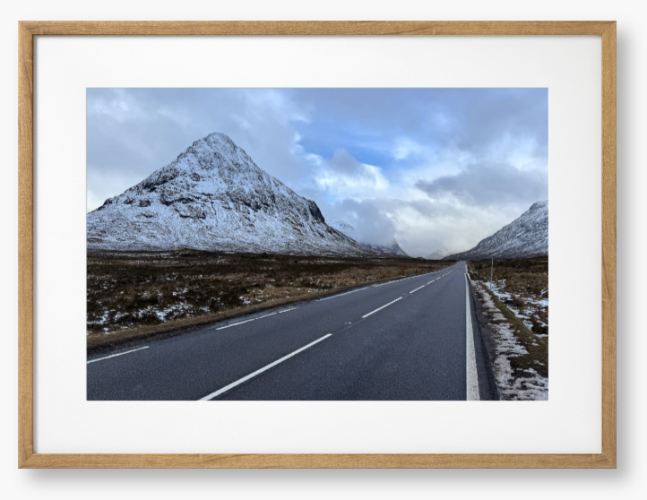 Framed Photo of a road leading towards snow-capped mountains under a cloudy sky