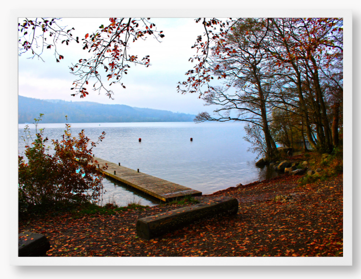 Framed Photo of a Autumn scene by a lake with a wooden jetty and trees with red leaves.
