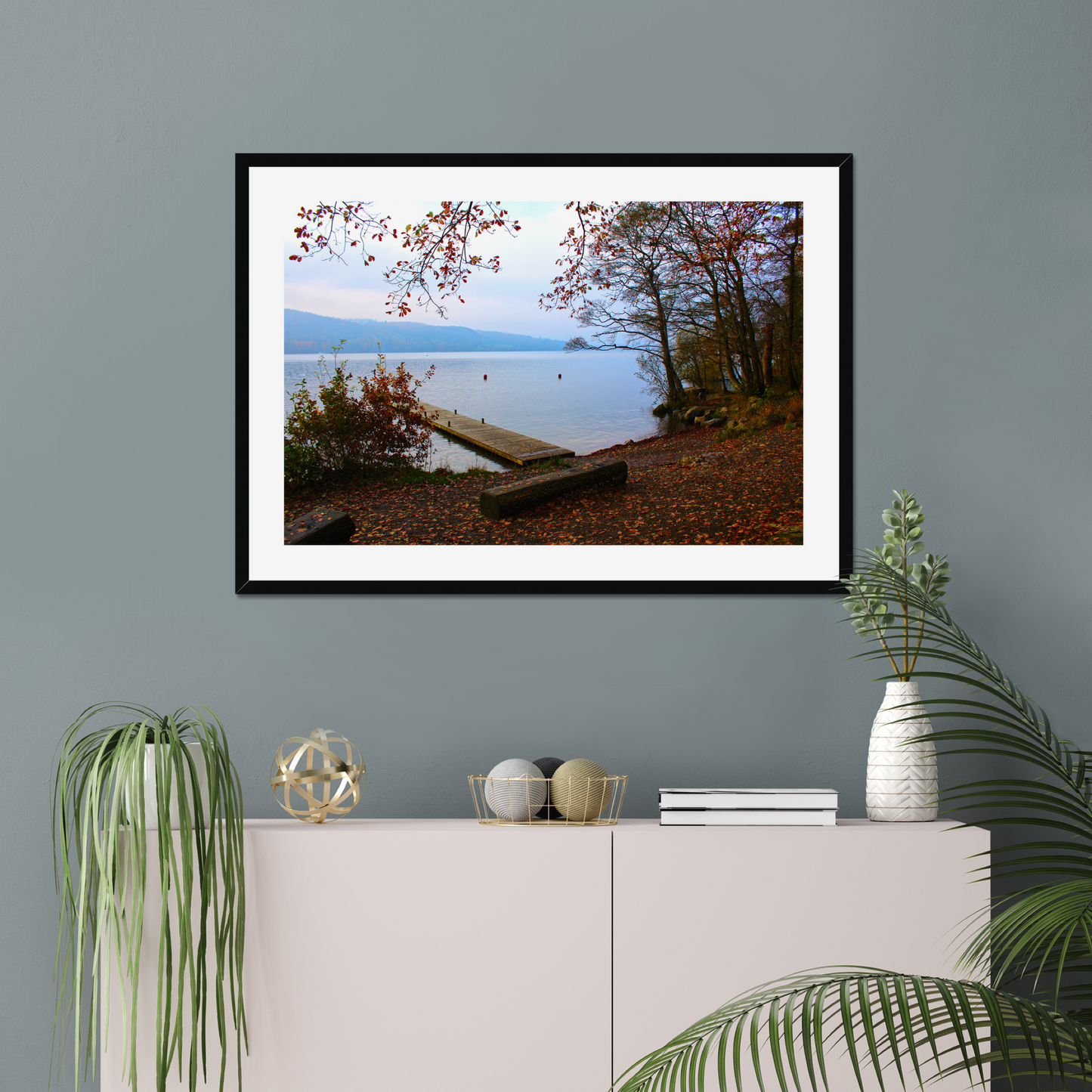 Framed photograph of a autumn scene by a lake with a wooden jetty and trees with red leaves.