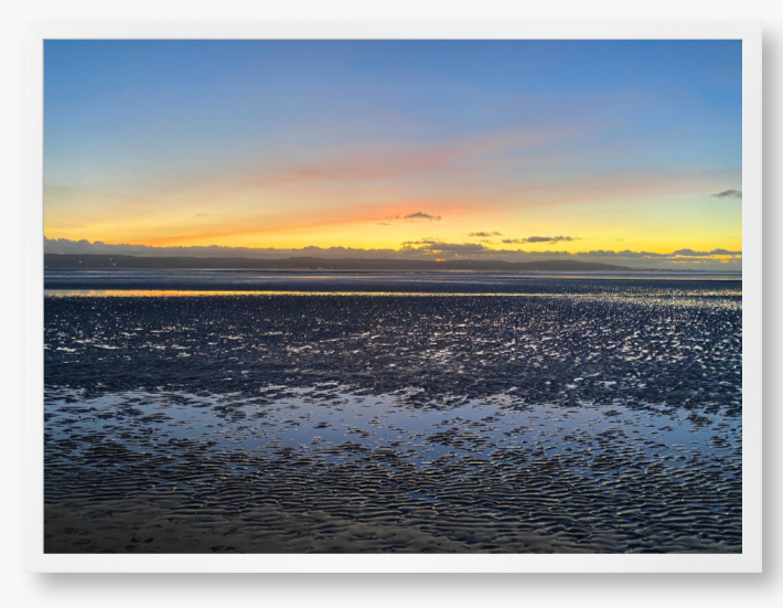 Framed Photo Of A Sunset over a calm body of water with a colorful sky.