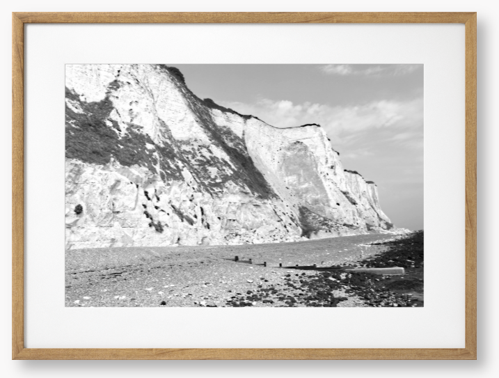 Black and white framed photograph of a coastal landscape with cliffs and beach.