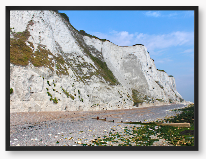 Framed Photo of White cliffs with a pebbly beach and blue sky