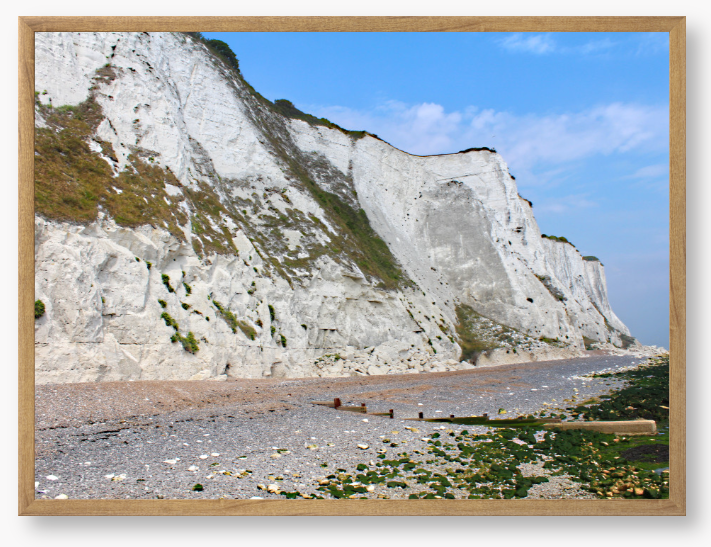 Framed Photo of White cliffs with a pebbly beach and blue sky