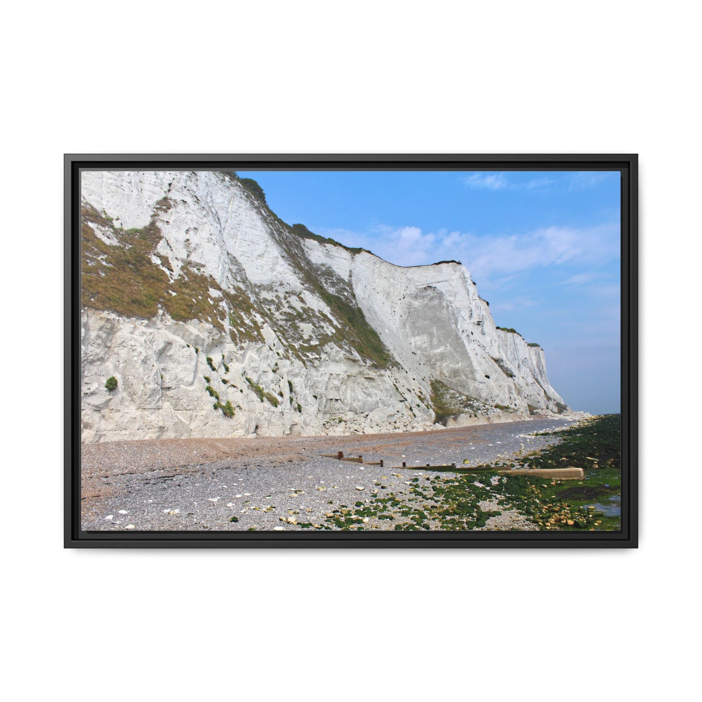 Framed photograph of white cliffs and a beach with a clear blue sky.