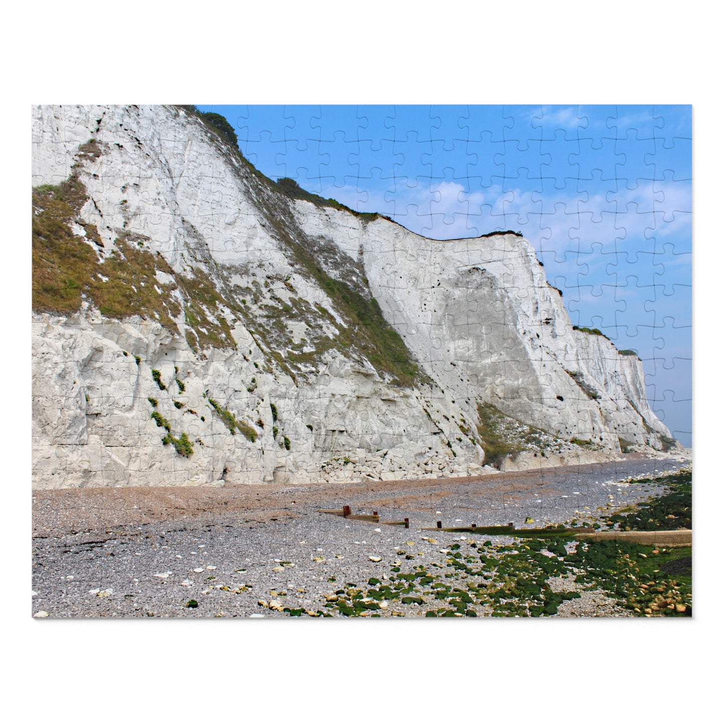 Cliffside landscape with white cliffs, blue sky, and beach.