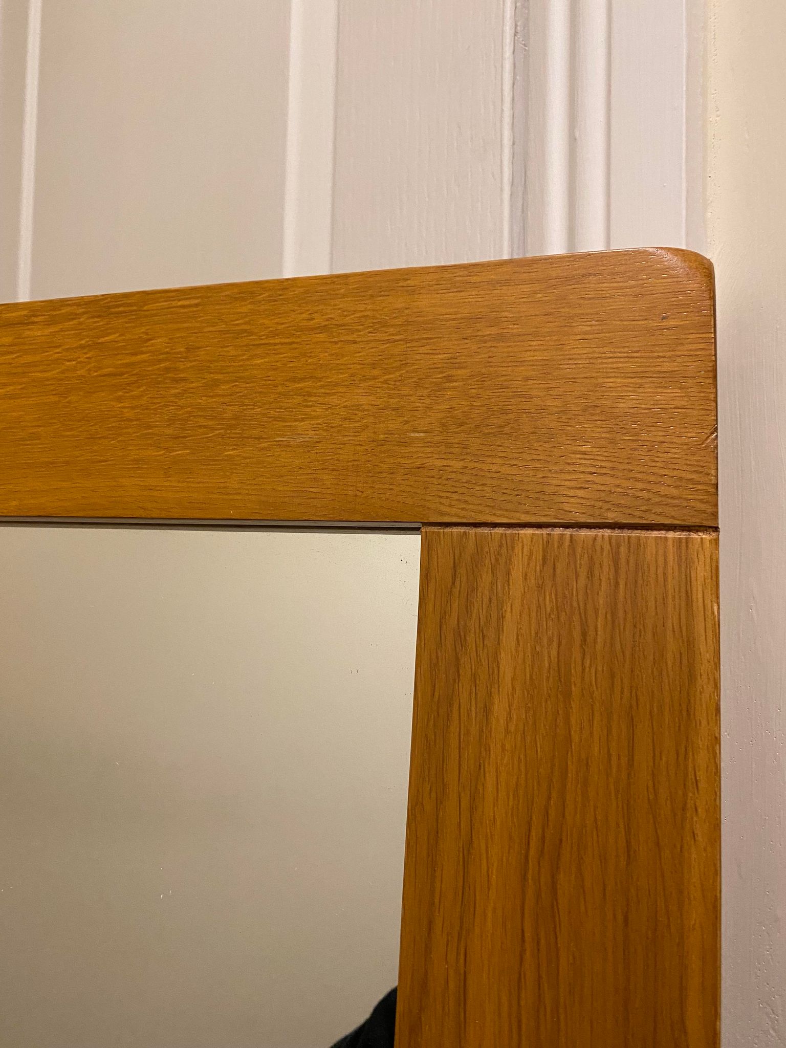Corner of a solid oak frame around a mirror.