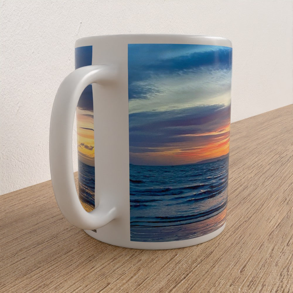 White mug with a sunset over water design on a wooden surface
