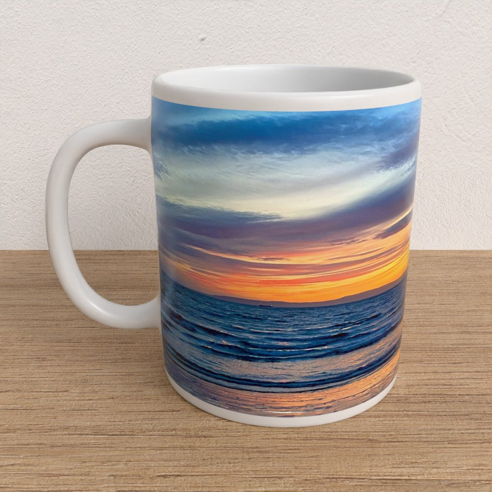 Mug with a sunset over ocean design on a wooden surface